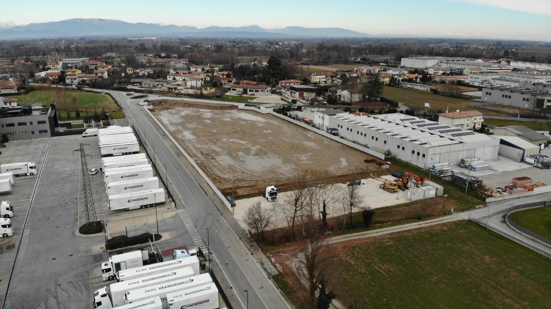 Luftaufnahme des planierten Industriegrundstücks vor dem Bau, zwischen den bestehenden Hallen